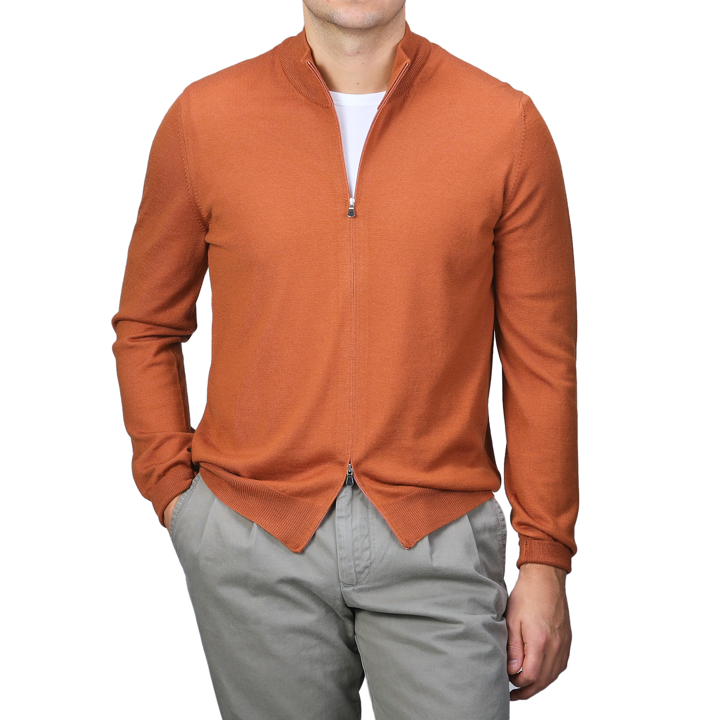 A person is stylishly wearing a Sienna Brown Extrafine Merino Wool Zip Cardigan from Gran Sasso, featuring its elegant merino wool fabric over a white shirt with gray pants.