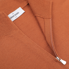 Close-up of a sienna brown extrafine merino wool zip cardigan with a half-zip design, showcasing a visible label that reads "Gran Sasso, Italy.