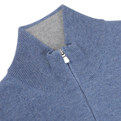 A close-up of the Gran Sasso Sky Blue Cashmere 1/4 Zip Sweater showcases its ribbed zip-up design and high collar, complete with a metal zipper pull. This premium knitwear piece is accented by a contrasting gray lining for enhanced style.