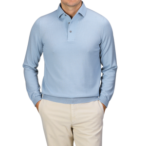 Against a plain gray backdrop, a man stands with his hands in his pockets, wearing the Gran Sasso Sky Blue Merino Wool One-Piece Collar Polo Shirt paired with beige pants.