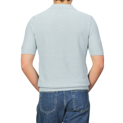 Back view of a person wearing a light gray short-sleeve textured polo shirt, Turquoise Cotton Linen by Gran Sasso, paired with blue jeans against a gray background.