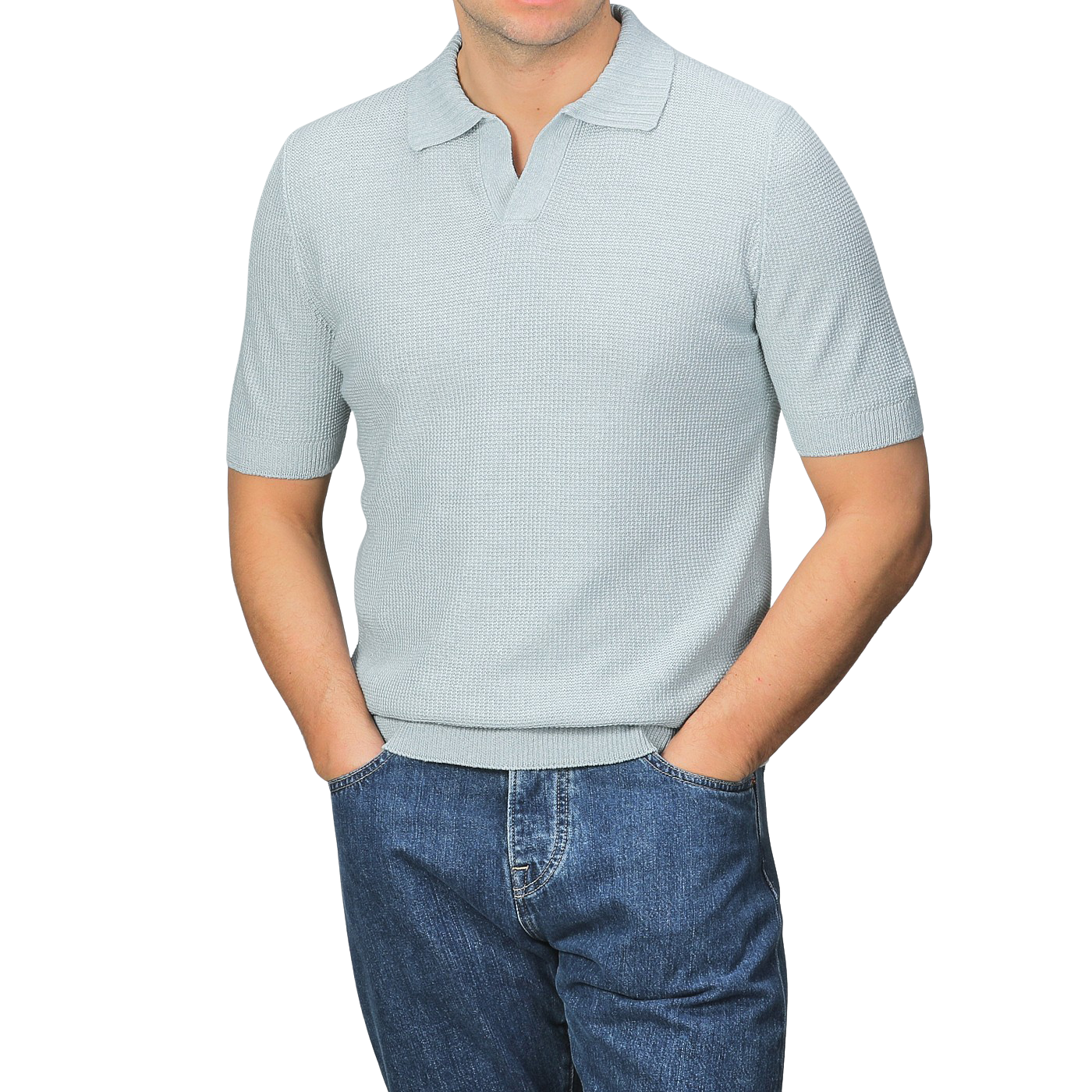 A person wearing a slim fit, turquoise cotton linen polo shirt by Gran Sasso and blue jeans stands with hands in pockets against a plain grey background.