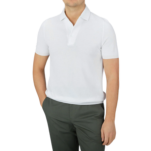 A man wears a Gran Sasso White Fresh Cotton Mesh Polo Shirt, known for its breathability, paired with dark pants and stands with hands in pockets.