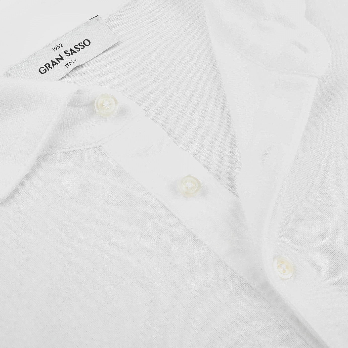 Close-up of a white Gran Sasso White Washed Cotton Popover Shirt in jersey, showcasing three buttons, its collar, and a tag labeled "Gran Sasso, Italy.