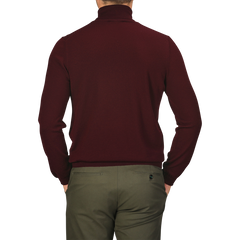 A man wearing a Gran Sasso Wine Melange Extra Fine Merino Roll Neck and dark green trousers is shown from the back.