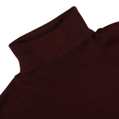 Close-up image of the Wine Melange Extra Fine Merino Roll Neck by Gran Sasso, crafted from extra fine merino wool, lying flat on a white surface.