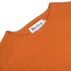 A Sienna Orange Extrafine Lambswool Crewneck with a "Harley of Scotland" label at the neckline, highlighting knitwear craftsmanship.