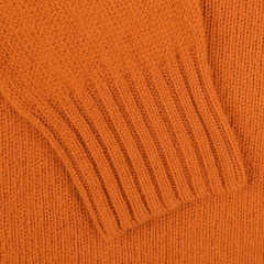 A close-up of the Harley of Scotland Sienna Orange Extrafine Lambswool Crewneck sweater showcases the ribbed cuff detail, highlighting their knitwear specialist expertise.