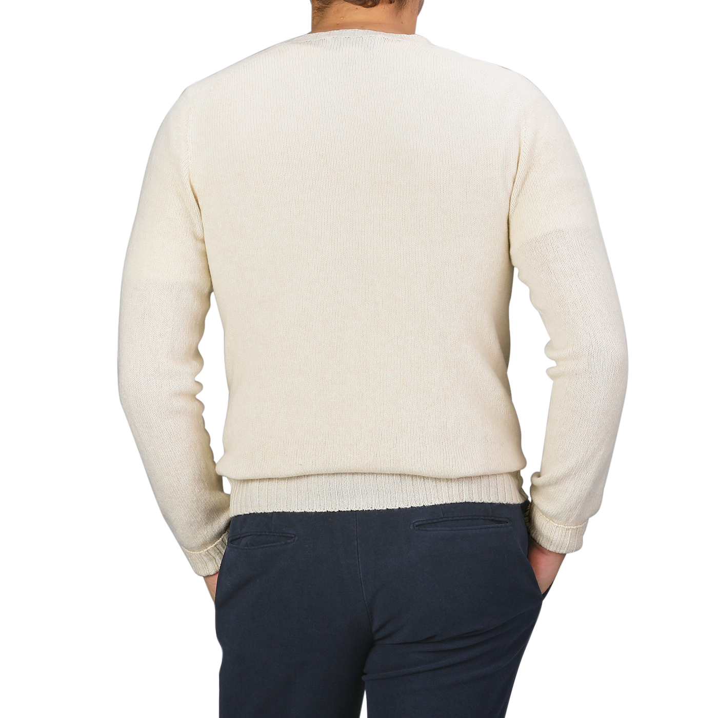 A person wearing an Almond White Extrafine Lambswool Crewneck by Harley of Scotland and dark pants, viewed from the back with hands in pockets.