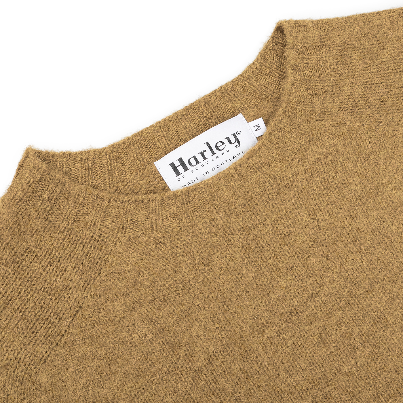 A close-up of an Asparagus Brushed Shaggy Wool Crewneck from Harley of Scotland highlights the label reading "Harley" and "Made in Scotland," exemplifying the brand's classic craftsmanship.