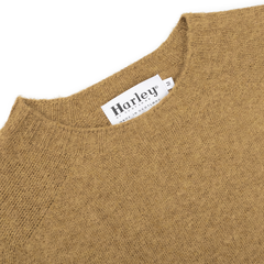 A close-up of an Asparagus Brushed Shaggy Wool Crewneck from Harley of Scotland highlights the label reading "Harley" and "Made in Scotland," exemplifying the brand's classic craftsmanship.