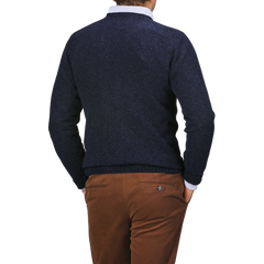 A person is shown from the back, wearing a Cosmos Blue Extrafine Lambswool Crewneck by Harley of Scotland and brown pants, with hands in pockets, exuding warmth and style.