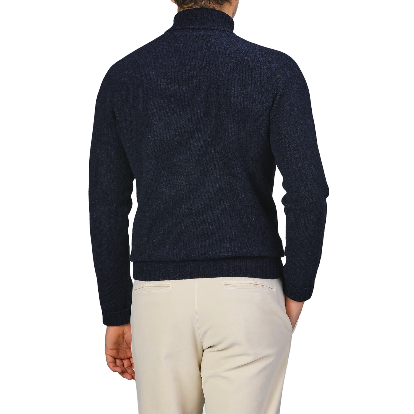 A person wearing a Harley of Scotland Cosmos Blue Extrafine Lambswool Rollneck sweater and light pants stands facing away against a neutral background.