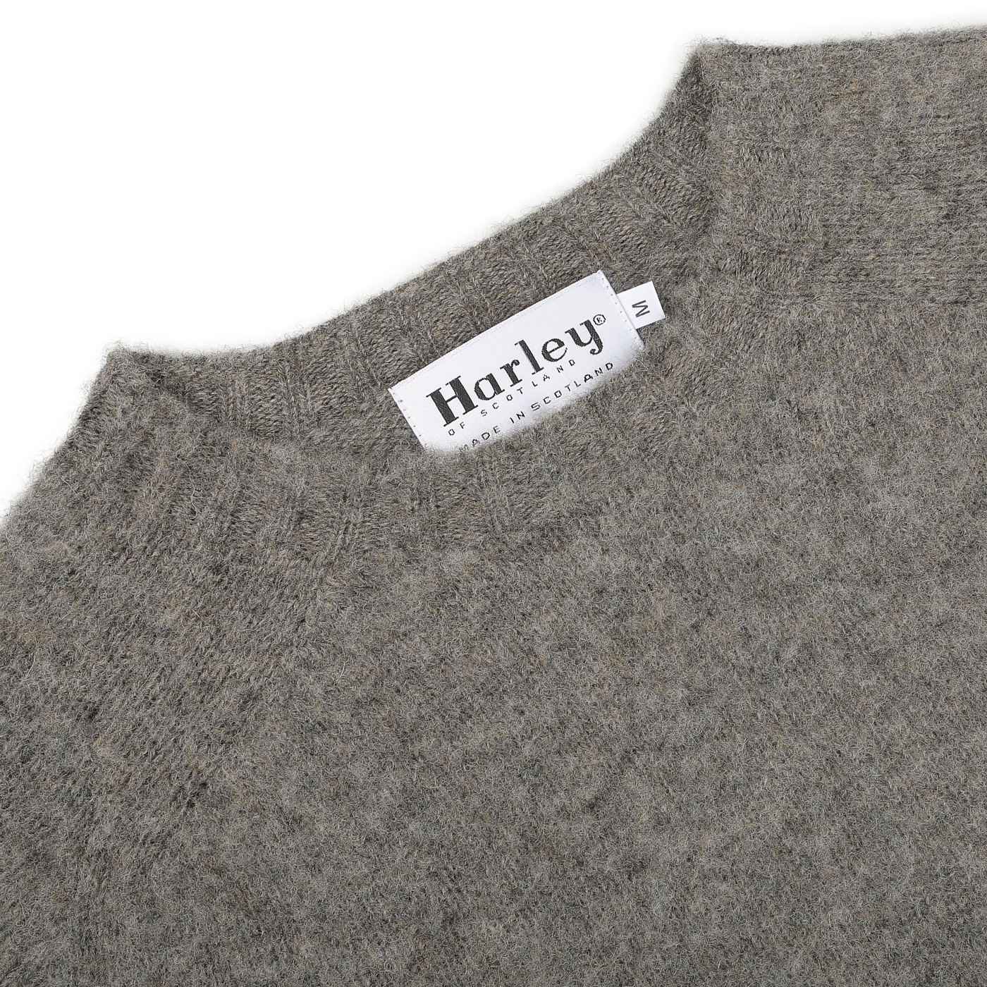 Close-up of an Oyster Grey Brushed Shaggy Wool Crewneck featuring the "Harley of Scotland" brand label and "Made in Scotland" text, showcasing the classic charm of its design.