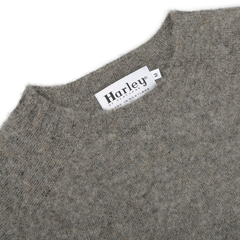 Close-up of an Oyster Grey Brushed Shaggy Wool Crewneck featuring the "Harley of Scotland" brand label and "Made in Scotland" text, showcasing the classic charm of its design.