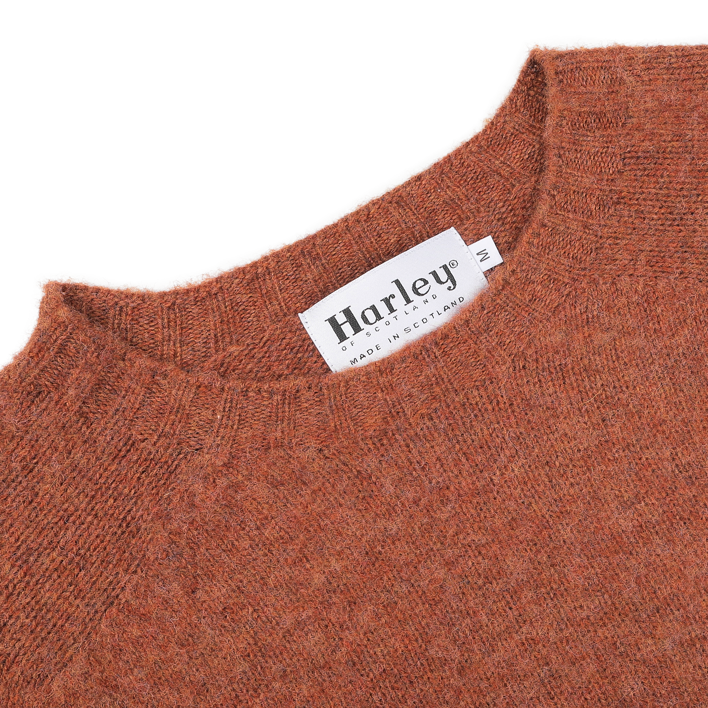 Close-up of the Sienna Brushed Shaggy Wool Crewneck in orange, showcasing the seamless knitting technique and featuring a tag that reads "Harley of Scotland, Made in Scotland.