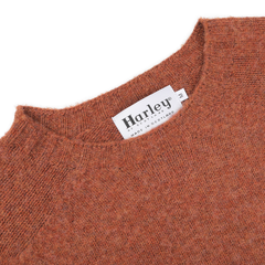 Close-up of the Sienna Brushed Shaggy Wool Crewneck in orange, showcasing the seamless knitting technique and featuring a tag that reads "Harley of Scotland, Made in Scotland.