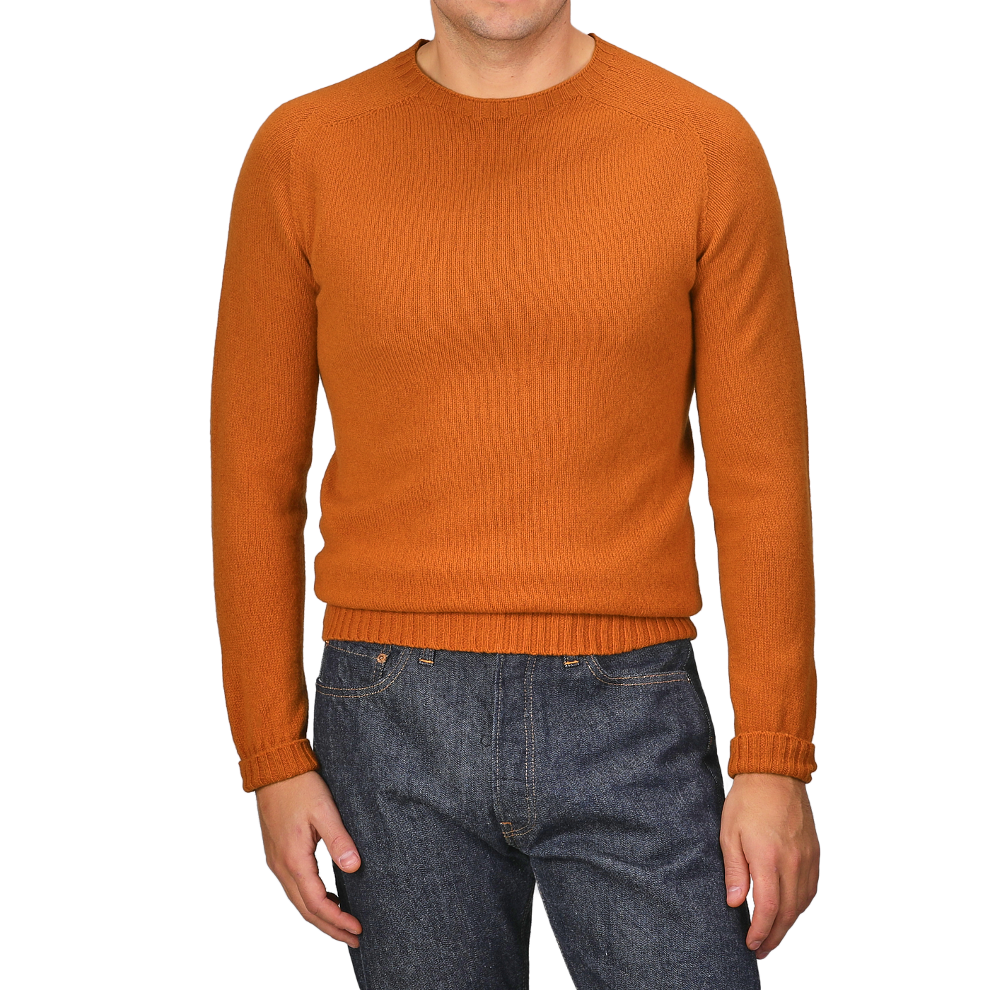 A person wearing the Sienna Orange Extrafine Lambswool Crewneck by Harley of Scotland and blue jeans stands against a gray background.