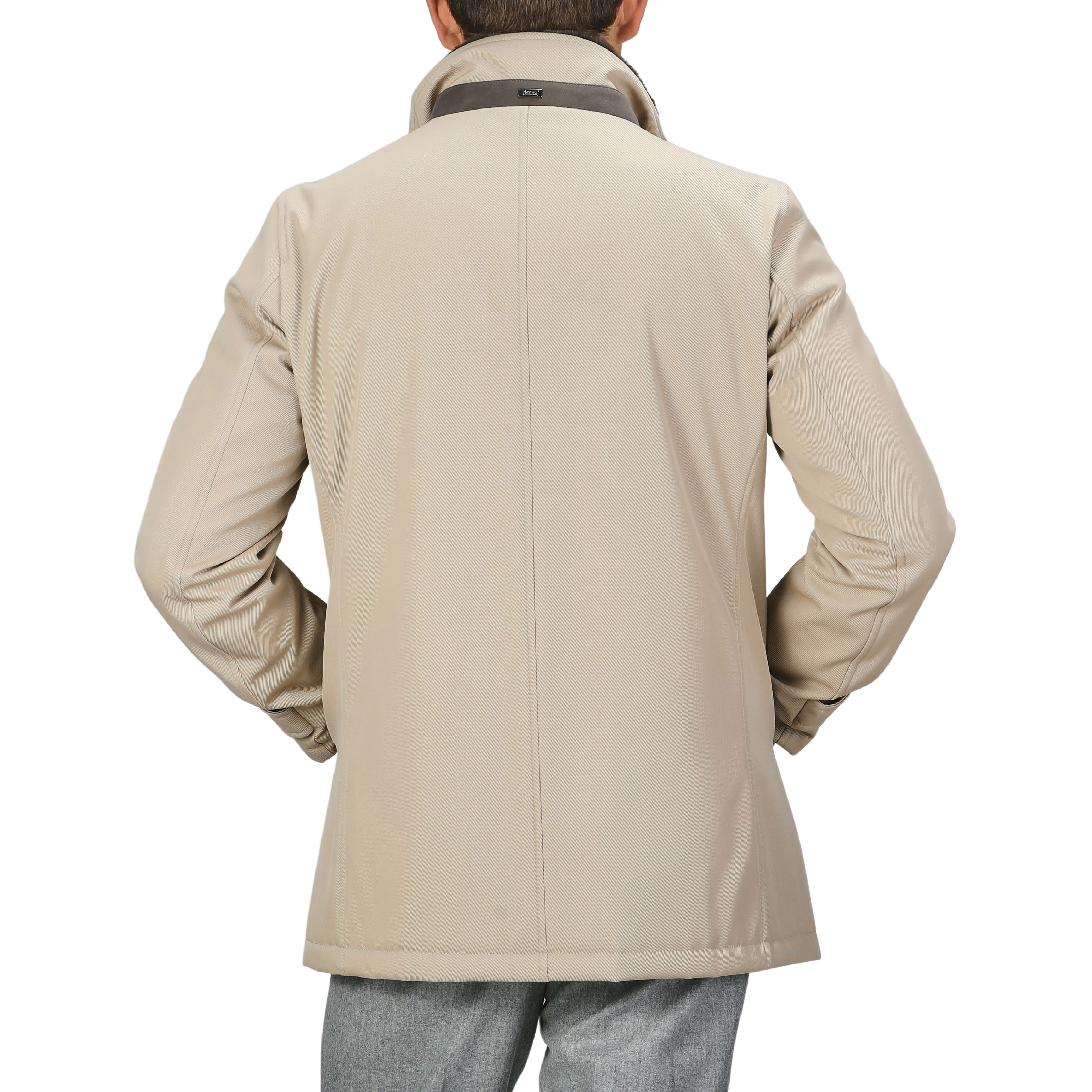 Rear view of a person wearing a luxurious Beige Loro Piana Wool Twill Jacket by Herno with a high collar and gray trousers, hands on hips.