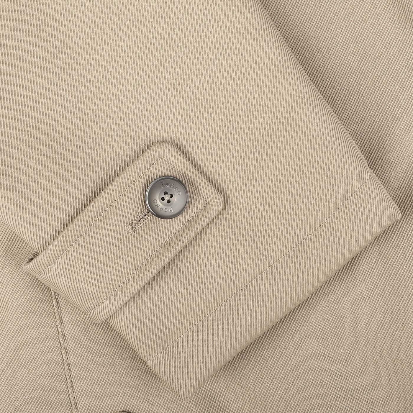 Close-up of a luxurious sleeve from the Herno Beige Loro Piana Wool Twill Jacket, featuring a single gray button and strap detail.