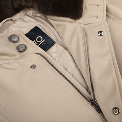 Close-up of the luxurious interior of the Beige Loro Piana Wool Twill Jacket by Herno, showcasing a metal zipper, buttons, and a black inner label with text. The rain- and wind-resistant jacket is partially unzipped, revealing its cream-colored lining.