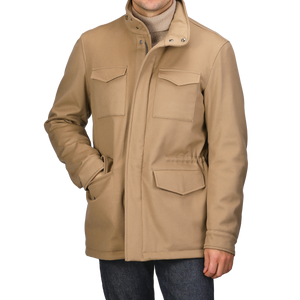 A person is wearing a Camel Beige Loro Piana Wool Field Jacket by Herno, featuring a high collar and flap pockets, with hands tucked in. The stylish jacket, equipped with Rain System technology, pairs perfectly with a turtleneck and jeans.