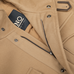 Close-up of a camel beige wool field jacket by Herno, showcasing a visible "Made in Italy" label. The Loro Piana coat, equipped with metal buttons and a zipper, is designed with Rain System technology for improved weather resistance.