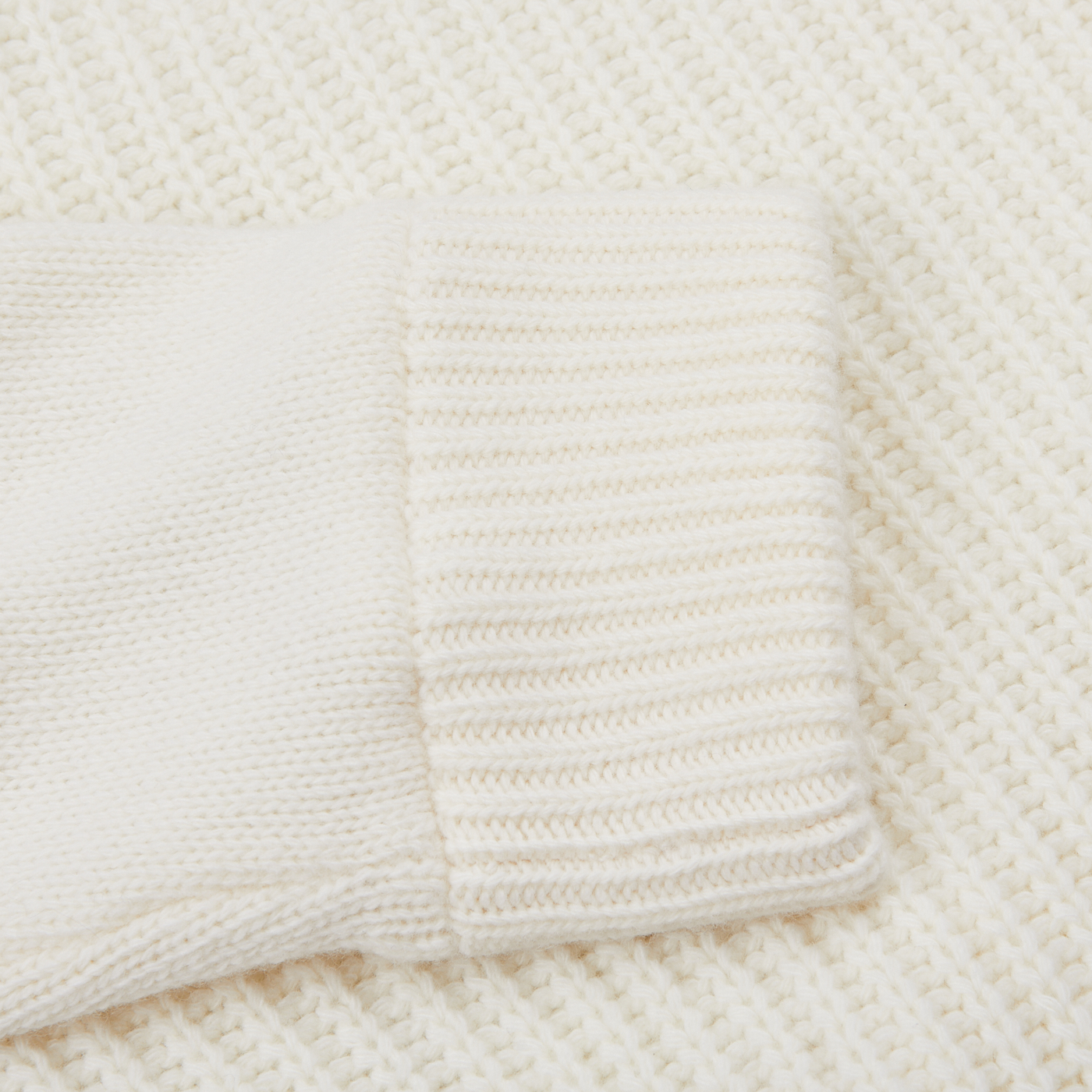 Close-up of the cuff of a Herno Cream Wool Nylon Reversible Knitted Jacket on top of another layer of similar virgin wool knit fabric. The textures and stitching patterns of the two knitted fabrics are visible.