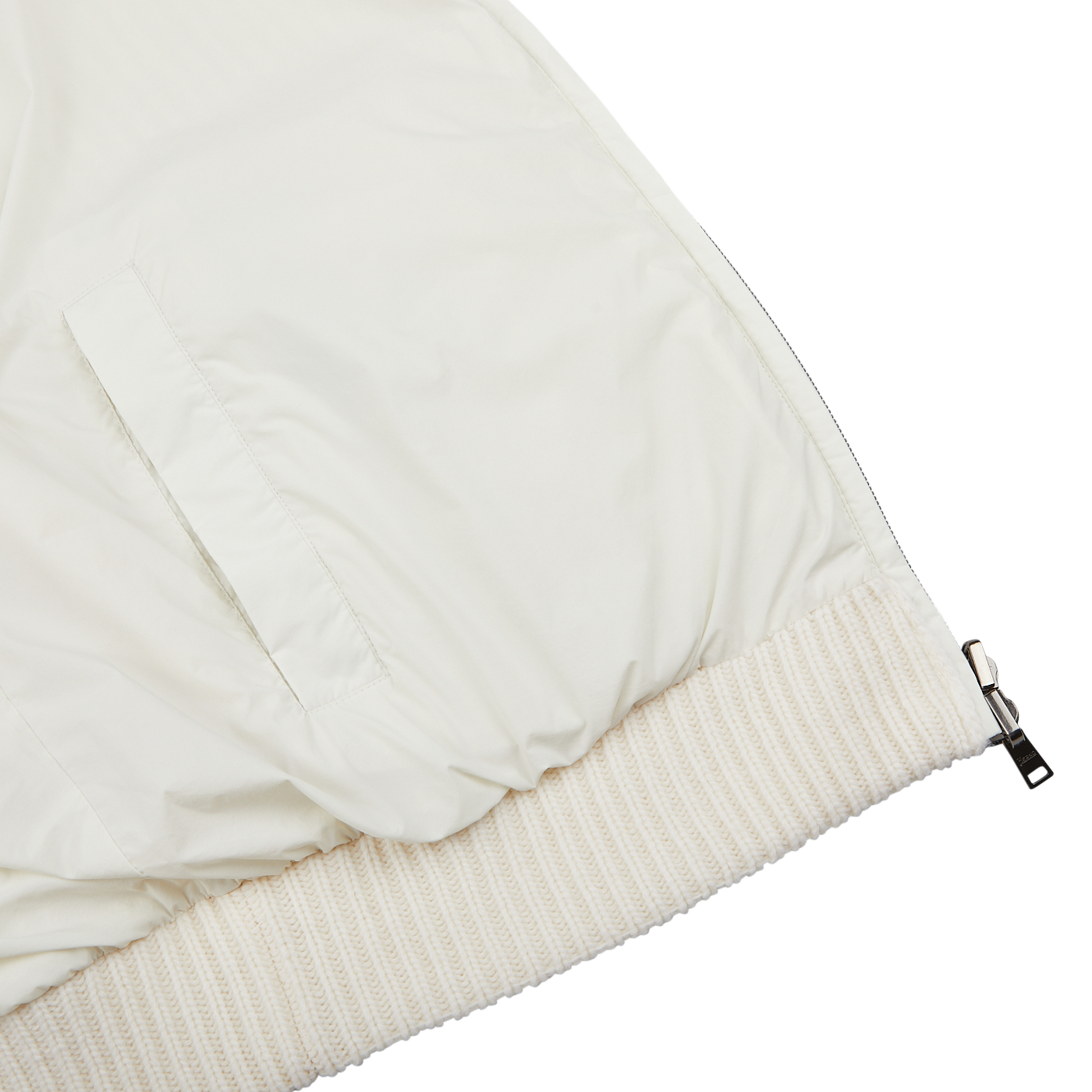 Close-up image of the lower portion of the Herno Cream Wool Nylon Reversible Knitted Jacket featuring a zippered pocket, ribbed hem, and a partial view of the zipper.