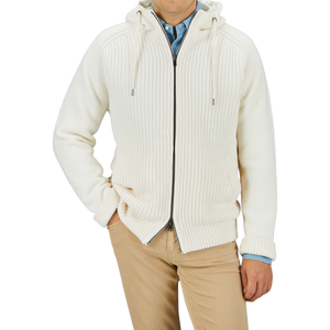 A person is wearing a Herno Cream Wool Nylon Reversible Knitted Jacket, crafted from virgin wool, with a front zipper over a blue shirt, paired with beige pants. The person's hands are in their pockets. Only the torso is visible.