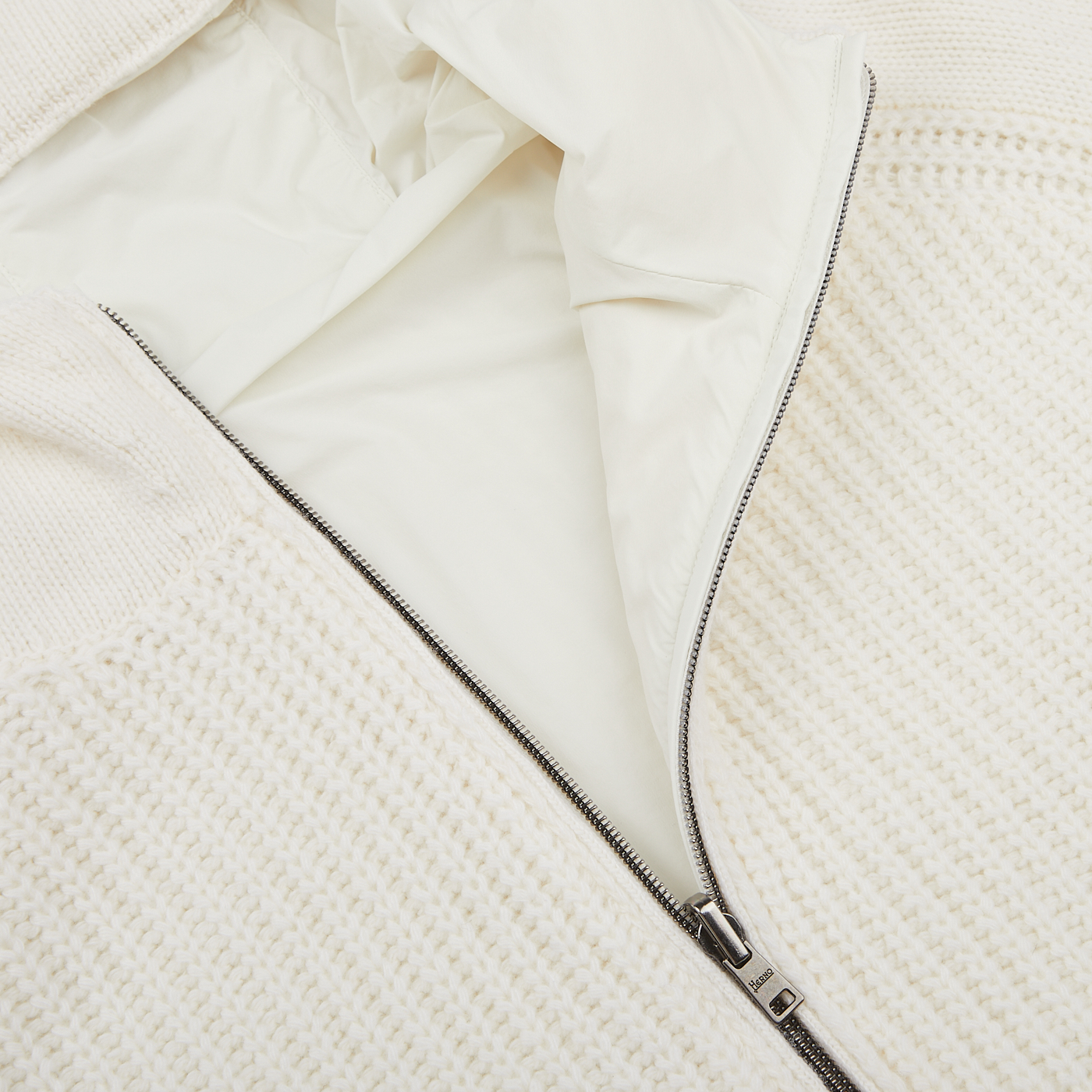 Close-up of a white **Herno** **Cream Wool Nylon Reversible Knitted Jacket** crafted from virgin wool, featuring a silver zipper, partially unzipped to reveal a white fabric lining.