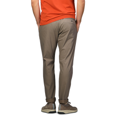 A person in an orange shirt stands with hands in pockets, facing away, wearing Herno's Dark Beige Nylon Stretch Drawstring Trousers.