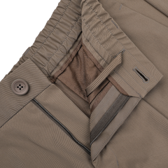 Close-up of Herno's dark beige nylon stretch drawstring trousers, featuring an open zipper, button closure, and elastic waistband for a blend of casual comfort and modern style with a slim fit.