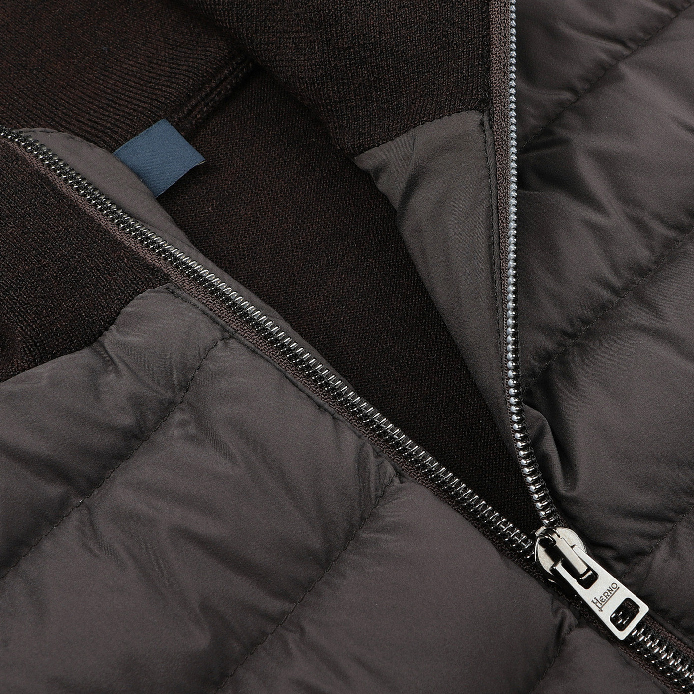 Close-up of a partially zipped Herno Dark Brown Wool Silk Nylon Padded Jacket featuring a metallic zipper and dark inner lining.