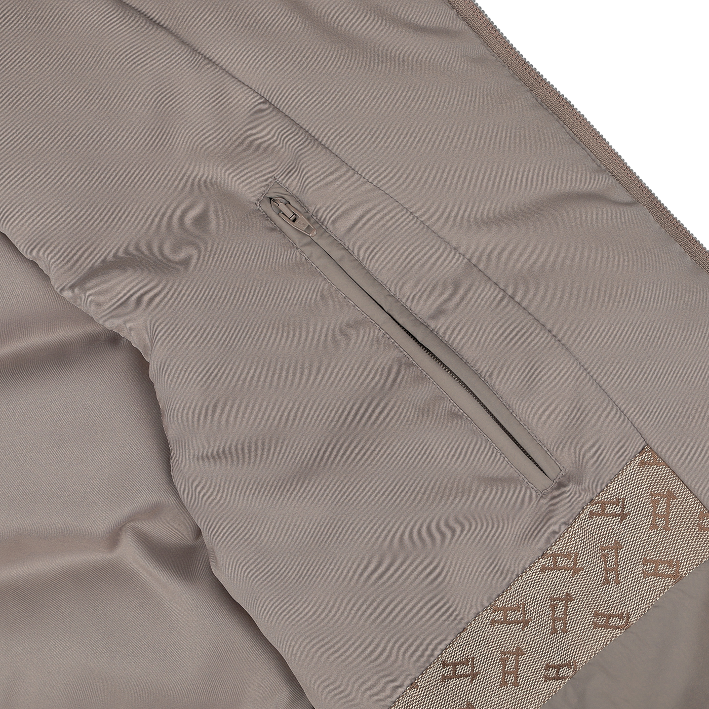 Close-up of the interior of a light beige nylon goose down quilted gilet from Herno, showcasing a zippered pocket and patterned lining with small "F" designs. The water-repellent fabric ensures durability, making it a practical choice for any weather.