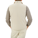 A person wearing a Herno Light Beige Suede Alcantara Zip Gilet over a gray long-sleeve shirt and light beige pants is photographed from the back against a plain background, showcasing a transitional style.