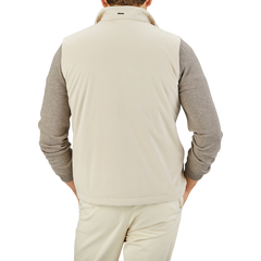 A person wearing a Herno Light Beige Suede Alcantara Zip Gilet over a gray long-sleeve shirt and light beige pants is photographed from the back against a plain background, showcasing a transitional style.