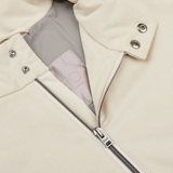 Close-up of a beige jacket with a partially unzipped metal zipper and snap button details, showcasing its Alcantara fabric interior and a portion of a pink label, perfect for transitional style. Herno Light Beige Suede Alcantara Zip Gilet.