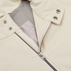 Close-up of a beige jacket with a partially unzipped metal zipper and snap button details, showcasing its Alcantara fabric interior and a portion of a pink label, perfect for transitional style. Herno Light Beige Suede Alcantara Zip Gilet.