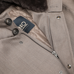 Close-up of a luxurious light brown wool twill jacket by Herno, featuring a rain-resistant black fur collar. The image showcases the buttons and includes a visible label reading "Made in Italy.