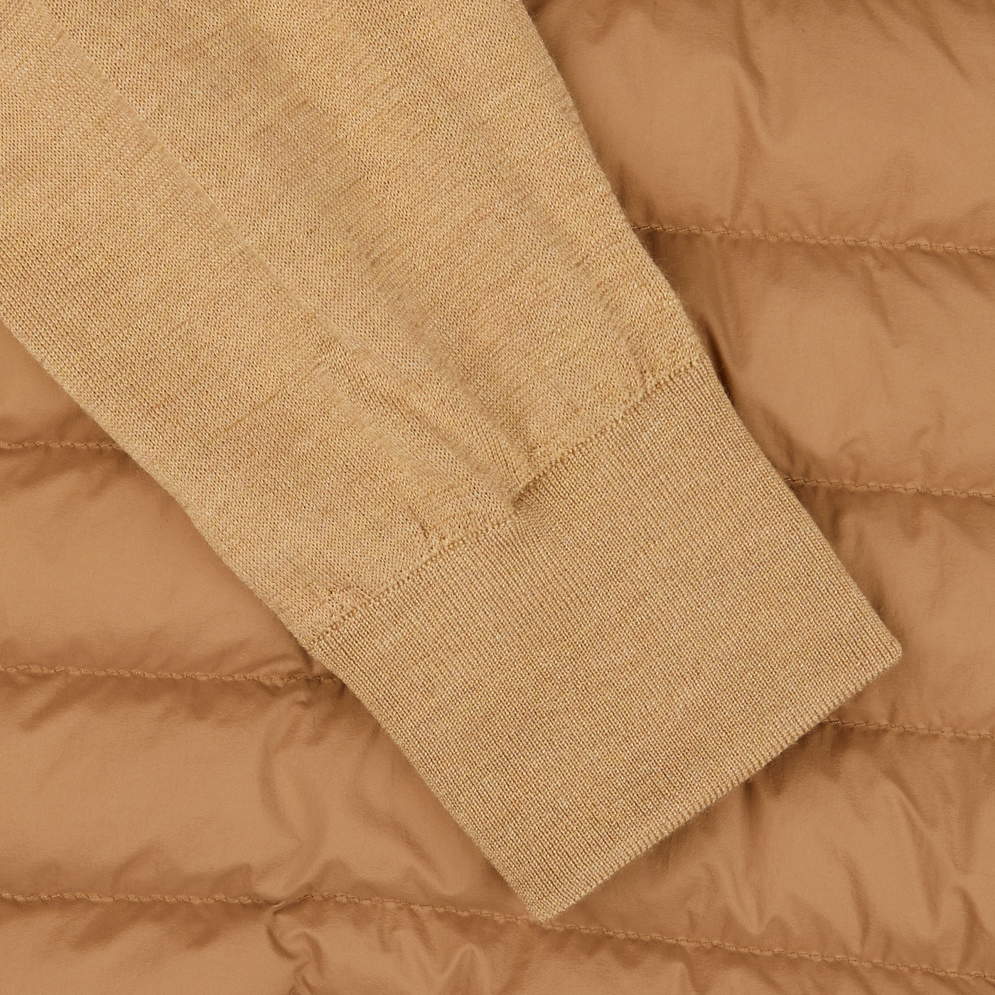 Close-up of a frayed Light Camel Wool Silk Nylon Padded Jacket cuff by Herno against a padded brown background.