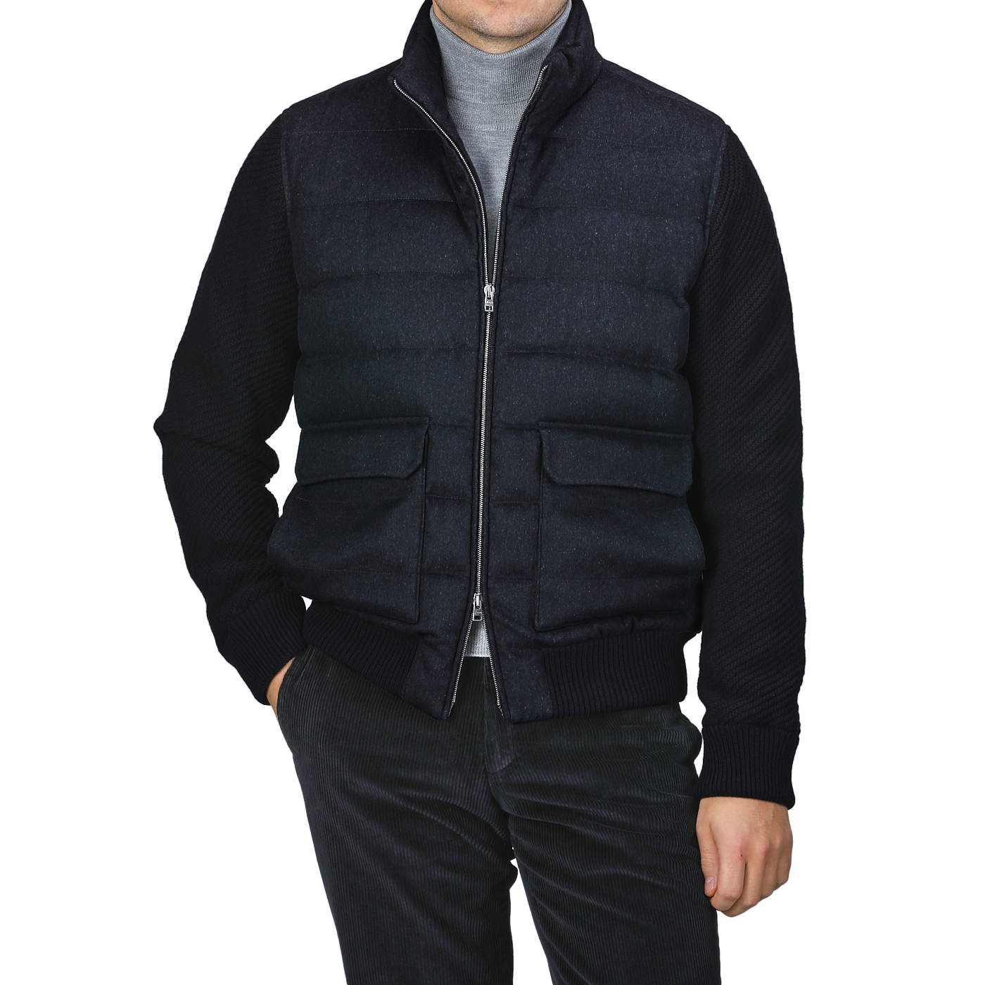 A man stands with his hands in his pockets, wearing a Navy Blue Cashmere Silk Bomber Jacket from Herno over a gray turtleneck and black pants.