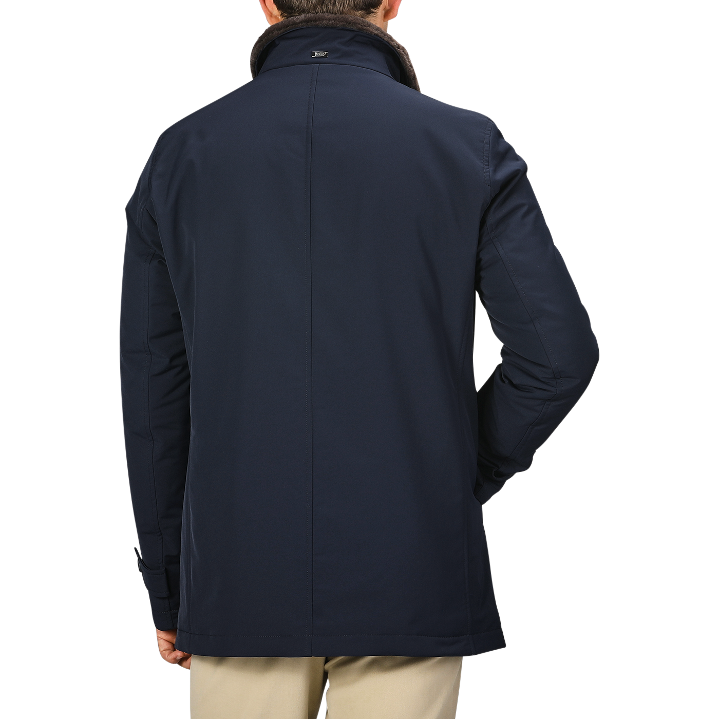 A man wearing a Herno Navy Blue Faux Fur Lined Nylon Car Coat and beige pants is seen from the back against a plain background. The slim fit of his technical nylon car coat adds a touch of modern style.