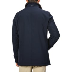 A man wearing a Herno Navy Blue Faux Fur Lined Nylon Car Coat and beige pants is seen from the back against a plain background. The slim fit of his technical nylon car coat adds a touch of modern style.