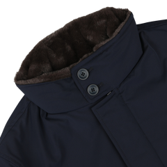 Close-up of the Navy Blue Faux Fur Lined Nylon Car Coat by Herno, showcasing a high buttoned collar lined with dark brown faux fur. The slim-fit coat features two buttons and a zipper on the collar.