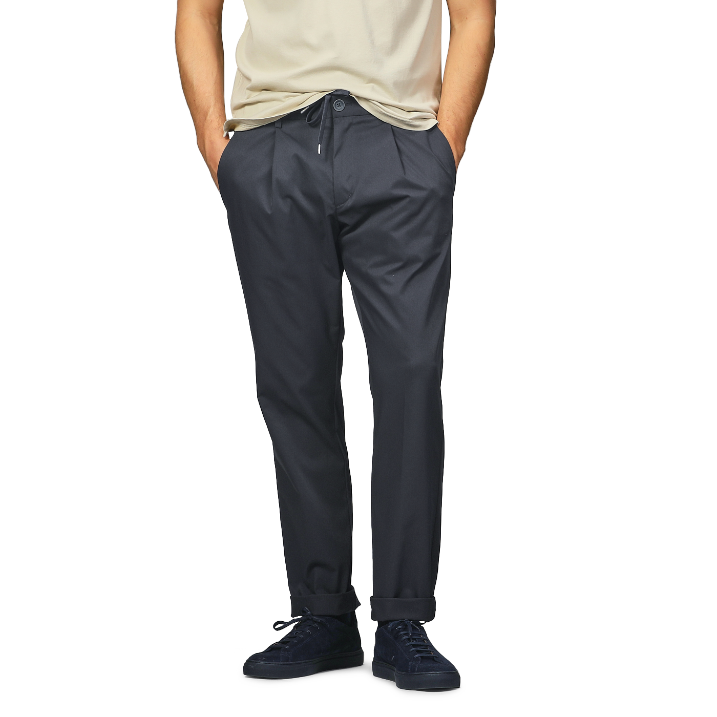 A person wearing a beige t-shirt, Herno's navy blue nylon stretch drawstring trousers, and black sneakers stands with hands in pockets.