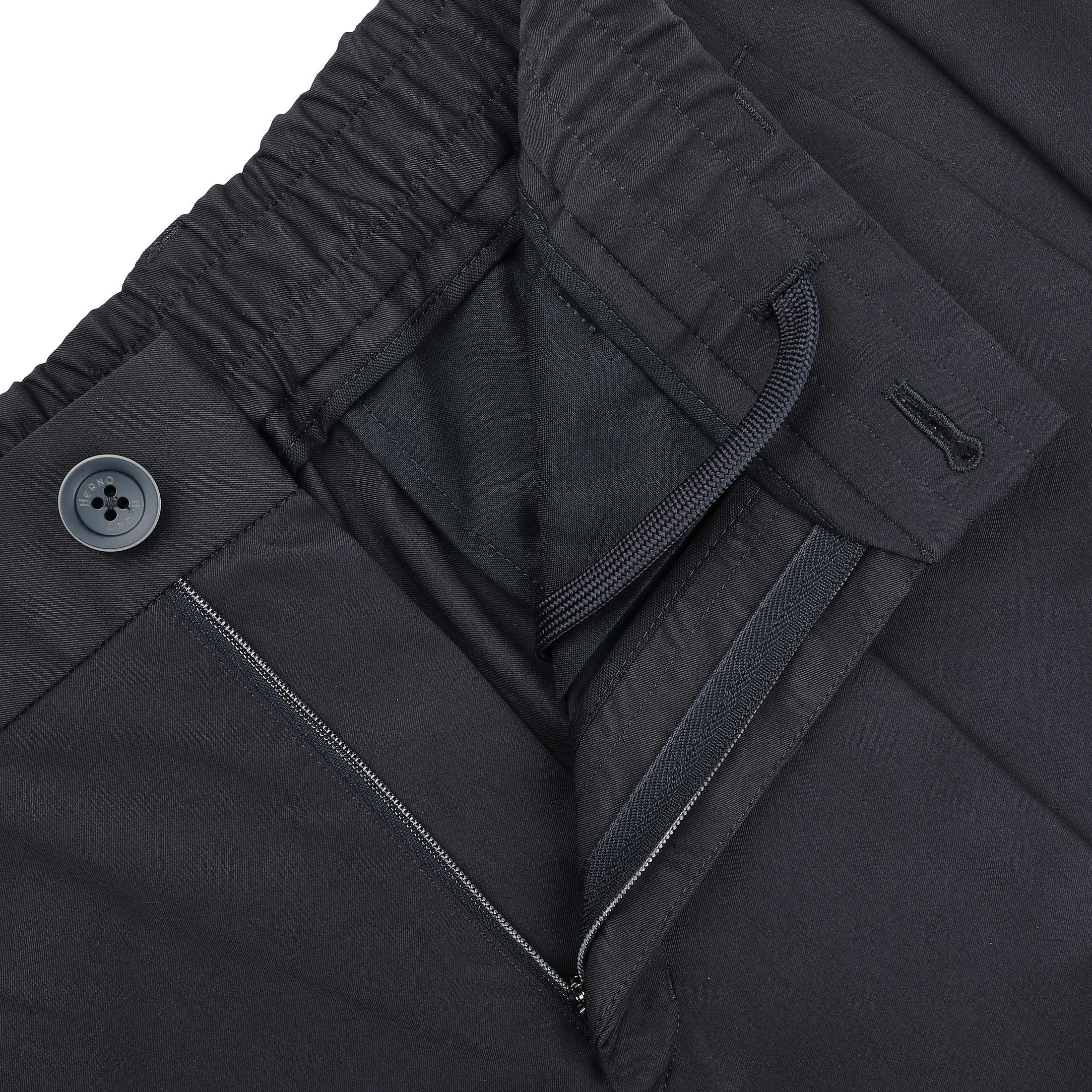 Close-up of slim fit navy blue nylon stretch trousers from Herno, featuring an elastic waistband with drawstring, button closure, and a visible zippered pocket.