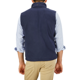 A man is shown from the back, wearing a Herno Navy Blue Suede Alcantara Zip Gilet over a light blue, rolled-up sleeve shirt and light khaki pants.