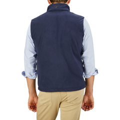 A man is shown from the back, wearing a Herno Navy Blue Suede Alcantara Zip Gilet over a light blue, rolled-up sleeve shirt and light khaki pants.