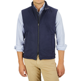 A person is wearing a Herno Navy Blue Suede Alcantara Zip Gilet, a light blue striped shirt with rolled-up sleeves, and beige pants against a light gray background.